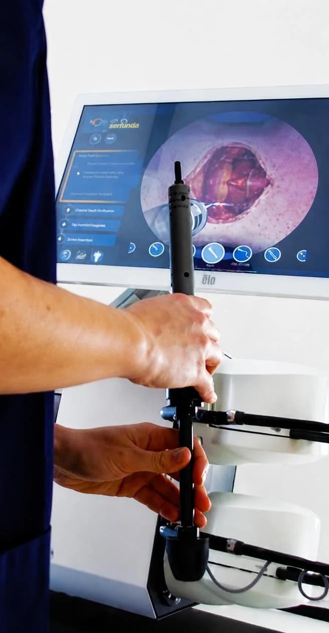 Hands guiding a surgical instrument handle on the Tsym haptic robot